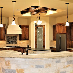 Photo of a large country u-shaped eat-in kitchen in Other with a farmhouse sink, raised-panel cabinets, dark wood cabinets, granite benchtops, beige splashback, travertine splashback, stainless steel appliances, travertine floors, with island, beige floor and grey benchtop.