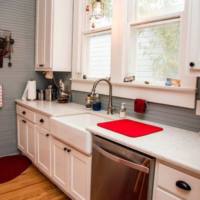 Mid-sized country galley dark wood floor and brown floor open concept kitchen photo in Austin with a farmhouse sink, shaker cabinets, white cabinets, quartz countertops, gray backsplash, stainless steel appliances and an island