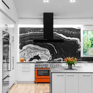Design ideas for a midcentury l-shaped kitchen in Houston with an undermount sink, flat-panel cabinets, grey cabinets, black splashback, stone slab splashback, stainless steel appliances, light hardwood floors, with island and beige floor.