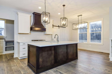 Inspiration for a medium sized traditional l-shaped open plan kitchen in Grand Rapids with a submerged sink, shaker cabinets, white cabinets, white splashback, stainless steel appliances, dark hardwood flooring, an island, brown floors and white worktops.