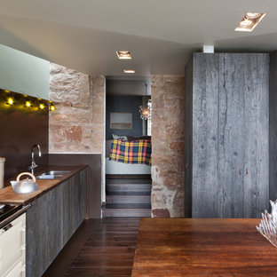 Design ideas for a medium sized rustic single-wall kitchen/diner in London with a double-bowl sink, dark hardwood flooring, an island, brown floors, flat-panel cabinets, grey cabinets, wood worktops, brown splashback and brown worktops.