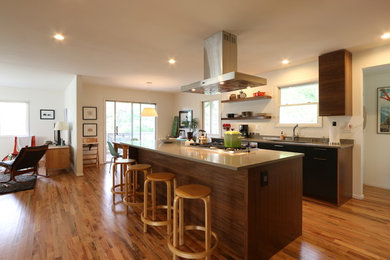Imagen de cocina contemporánea abierta con armarios con paneles lisos, puertas de armario de madera en tonos medios, suelo de madera en tonos medios y una isla
