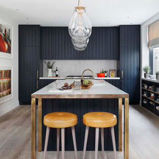 Photo of a large classic l-shaped kitchen/diner in London with a submerged sink, blue cabinets, grey splashback, porcelain splashback, integrated appliances, an island, grey floors, white worktops and flat-panel cabinets.
