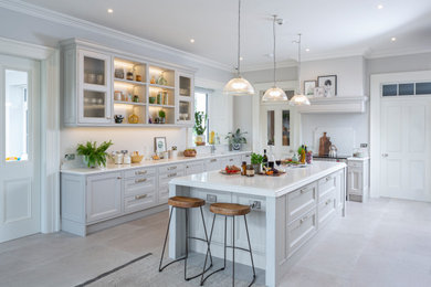 Design ideas for a traditional u-shaped kitchen/diner in Other with a submerged sink, recessed-panel cabinets, grey cabinets, white splashback, integrated appliances, an island, beige floors and white worktops.