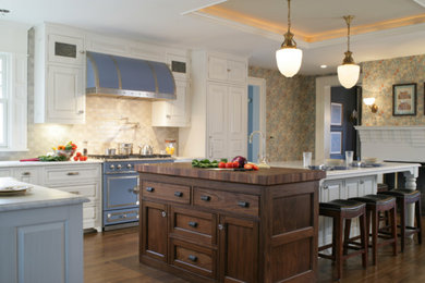 Example of a classic l-shaped eat-in kitchen design in New York with a farmhouse sink, raised-panel cabinets, white cabinets, marble countertops, gray backsplash, ceramic backsplash and colored appliances
