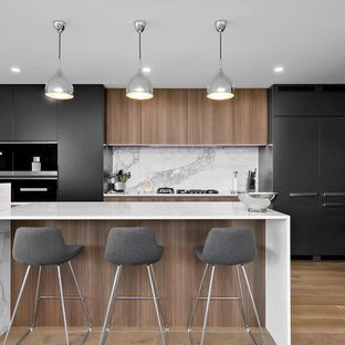 Inspiration for a large contemporary galley open plan kitchen in Sydney with an integrated sink, black cabinets, quartz benchtops, grey splashback, marble splashback, stainless steel appliances, medium hardwood floors, with island, brown floor, white benchtop and flat-panel cabinets.