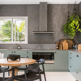 Mid-sized beach style l-shaped eat-in kitchen in Other with green cabinets, grey splashback, white floor, brown benchtop, an undermount sink and stainless steel appliances.