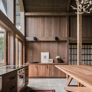 This is an example of a large country open plan kitchen in Brisbane with a farmhouse sink, shaker cabinets, medium wood cabinets, wood benchtops, white appliances, slate floors, with island and grey floor.