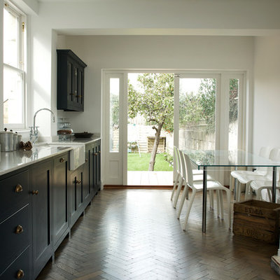 Example of a trendy dark wood floor eat-in kitchen design in Other with a farmhouse sink, shaker cabinets and blue cabinets
