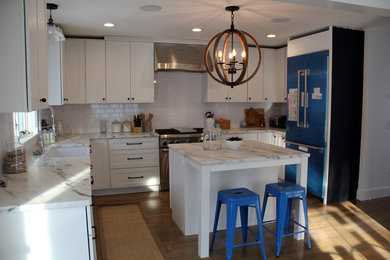 Example of a mid-sized country l-shaped light wood floor eat-in kitchen design in Other with a farmhouse sink, shaker cabinets, white cabinets, marble countertops, white backsplash, subway tile backsplash, stainless steel appliances and an island
