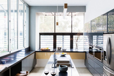 Foto på ett stort funkis kök, med en nedsänkt diskho, släta luckor, rostfria vitvaror, en köksö och svarta skåp