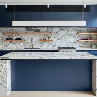 Photo of a mid-sized modern l-shaped eat-in kitchen in Melbourne with an undermount sink, flat-panel cabinets, blue cabinets, marble benchtops, white splashback, marble splashback, black appliances, light hardwood floors, with island, beige floor and white benchtop.