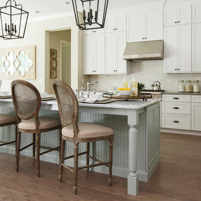 Kitchen - large traditional galley dark wood floor and brown floor kitchen idea in Jacksonville with shaker cabinets, white cabinets, white backsplash, stainless steel appliances, an island, an undermount sink, marble countertops and porcelain backsplash
