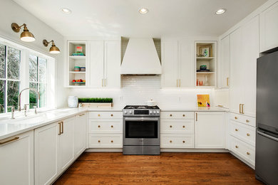 Example of a large farmhouse u-shaped medium tone wood floor and brown floor eat-in kitchen design in Dallas with shaker cabinets, white cabinets, white backsplash, stainless steel appliances, white countertops, an undermount sink, quartz countertops, subway tile backsplash and no island