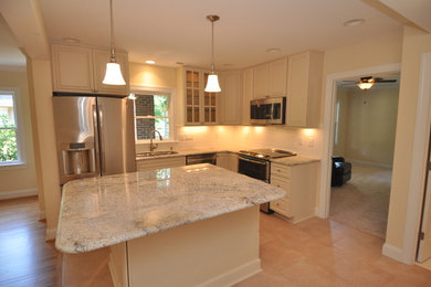Foto di una cucina classica di medie dimensioni con lavello a doppia vasca, ante bianche, paraspruzzi bianco, elettrodomestici in acciaio inossidabile, pavimento con piastrelle in ceramica e top in granito