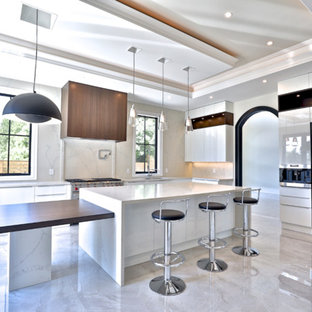 Mid-sized modern u-shaped separate kitchen in Toronto with a double-bowl sink, flat-panel cabinets, white cabinets, limestone benchtops, beige splashback, limestone splashback, stainless steel appliances, laminate floors, multiple islands, beige floor and white benchtop.