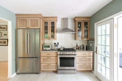 Inspiration for a mid-sized timeless galley porcelain tile and gray floor eat-in kitchen remodel in New York with a farmhouse sink, recessed-panel cabinets, distressed cabinets, quartz countertops, white backsplash, subway tile backsplash, stainless steel appliances, a peninsula and gray countertops