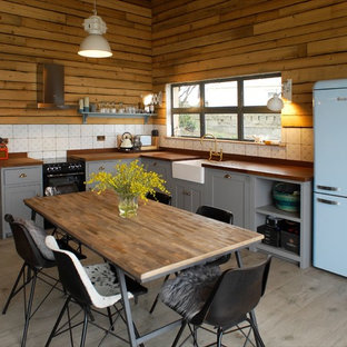 This is an example of a rural l-shaped kitchen/diner in London with a belfast sink, shaker cabinets, grey cabinets, wood worktops, white splashback, no island and grey floors.