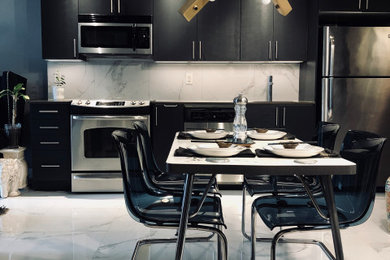 Example of a small trendy single-wall porcelain tile and white floor eat-in kitchen design in Toronto with an undermount sink, flat-panel cabinets, black cabinets, quartz countertops, white backsplash, porcelain backsplash, stainless steel appliances and gray countertops