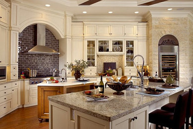 Inspiration for a large traditional kitchen in Tampa with a double-bowl sink, shaker cabinets, white cabinets, granite worktops, brown splashback, stone tiled splashback, stainless steel appliances, medium hardwood flooring and multiple islands.