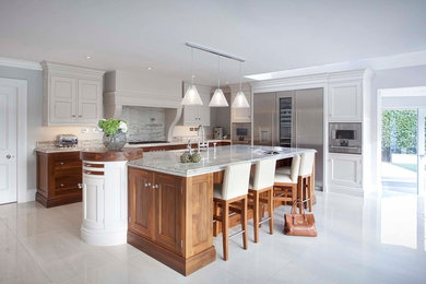 Photo of a medium sized traditional l-shaped kitchen in Other with recessed-panel cabinets, medium wood cabinets, marble worktops, white splashback, marble splashback, an island and white floors.