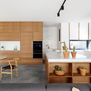 Design ideas for a contemporary l-shaped open plan kitchen in Canberra - Queanbeyan with flat-panel cabinets, white cabinets, window splashback, concrete floors, with island, grey floor and white benchtop.