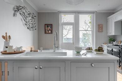 Photo of a medium sized classic u-shaped kitchen/diner in Surrey with a double-bowl sink, shaker cabinets, grey cabinets, quartz worktops, black appliances, no island and white worktops.