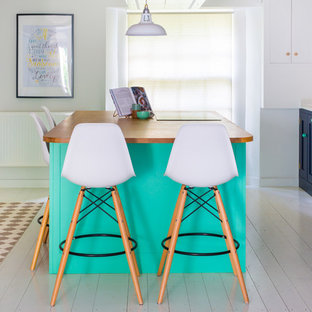 Large eclectic u-shaped eat-in kitchen in Other with a farmhouse sink, shaker cabinets, blue cabinets, quartzite benchtops, white splashback, subway tile splashback, painted wood floors, with island, white floor and white appliances.