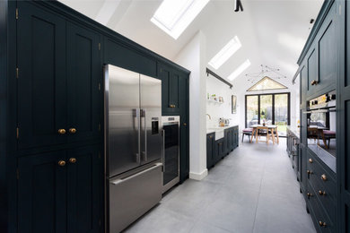 Inspiration for a large contemporary galley open plan kitchen in Essex with a belfast sink, shaker cabinets, green cabinets, quartz worktops, white splashback, mosaic tiled splashback, stainless steel appliances, cement flooring, no island, grey floors and white worktops.