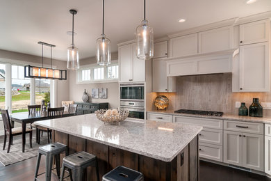 Mid-sized transitional u-shaped dark wood floor and brown floor eat-in kitchen photo in Milwaukee with a drop-in sink, recessed-panel cabinets, white cabinets, granite countertops, beige backsplash, porcelain backsplash, stainless steel appliances and an island