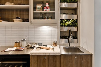 Example of a trendy kitchen design in Montreal with glass-front cabinets, matchstick tile backsplash, white backsplash, stainless steel countertops, an integrated sink and dark wood cabinets