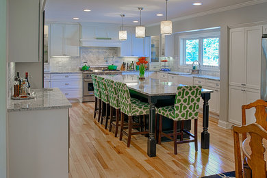 Mid-sized transitional u-shaped light wood floor eat-in kitchen photo in Minneapolis with a farmhouse sink, flat-panel cabinets, white cabinets, granite countertops, gray backsplash, stone tile backsplash, stainless steel appliances and an island