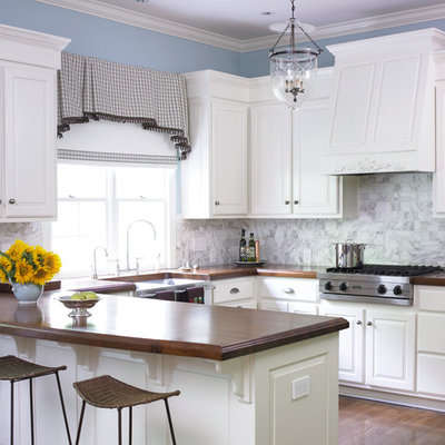 Inspiration for a timeless u-shaped kitchen remodel in Atlanta with a farmhouse sink, wood countertops, raised-panel cabinets, white cabinets, white backsplash and stone tile backsplash
