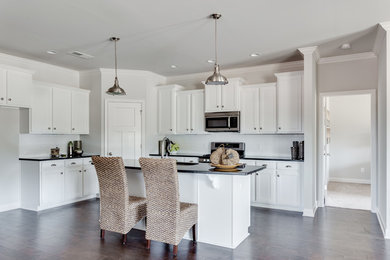 Open concept kitchen - mid-sized craftsman l-shaped dark wood floor open concept kitchen idea in Other with an undermount sink, recessed-panel cabinets, white cabinets, solid surface countertops, white backsplash, subway tile backsplash, stainless steel appliances and an island