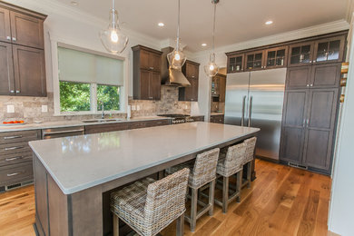 Inspiration for a mid-sized craftsman medium tone wood floor and beige floor enclosed kitchen remodel in Wilmington with dark wood cabinets, stainless steel appliances, an island, an undermount sink, recessed-panel cabinets, quartz countertops, beige backsplash and porcelain backsplash