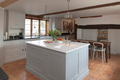 Photo of a traditional l-shaped kitchen/diner in London with a belfast sink, recessed-panel cabinets and grey cabinets.