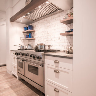 Photo of a mid-sized eclectic u-shaped open plan kitchen in Tampa with an undermount sink, shaker cabinets, white cabinets, limestone benchtops, white splashback, subway tile splashback, panelled appliances, light hardwood floors, with island, beige floor and grey benchtop.