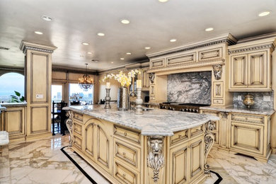 Kitchen - large traditional u-shaped marble floor kitchen idea in Orange County with an undermount sink, stone slab backsplash, stainless steel appliances, raised-panel cabinets, yellow cabinets, marble countertops, multicolored backsplash and an island