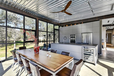 Inspiration for an industrial galley concrete floor and gray floor eat-in kitchen remodel in Austin with flat-panel cabinets, gray cabinets, an undermount sink, stainless steel appliances, an island and gray countertops