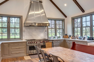 Huge farmhouse medium tone wood floor and brown floor eat-in kitchen photo in Calgary with a farmhouse sink, recessed-panel cabinets, gray cabinets, marble countertops, white backsplash, marble backsplash, stainless steel appliances, a peninsula and white countertops