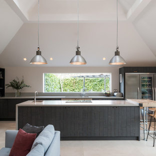 Large country open plan kitchen in Other with dark wood cabinets, composite countertops, stainless steel appliances, limestone flooring, a double-bowl sink, flat-panel cabinets, window splashback, beige floors, grey worktops and multiple islands.