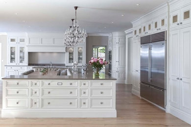 This is an example of a large classic kitchen in Other with raised-panel cabinets, an island and brown floors.
