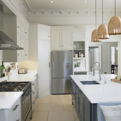Example of a large transitional kitchen design in London with shaker cabinets, white cabinets, quartz countertops, white backsplash, an island, a double-bowl sink and stainless steel appliances