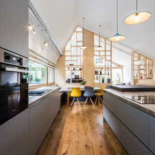 Design ideas for a large contemporary galley kitchen/diner in Other with a double-bowl sink, grey cabinets, wood worktops, window splashback, medium hardwood flooring, an island, brown floors and brown worktops.
