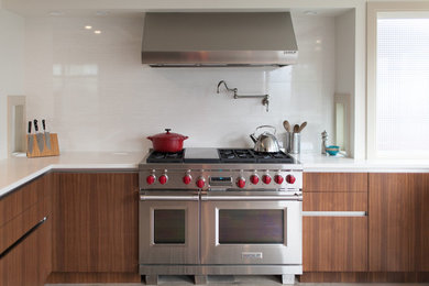Foto di una grande cucina abitabile moderna con lavello sottopiano, ante lisce, ante in legno scuro, paraspruzzi bianco, elettrodomestici in acciaio inossidabile e penisola
