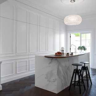 Ispirazione per una cucina vittoriana di medie dimensioni con lavello sottopiano, ante bianche, top in marmo, paraspruzzi bianco, paraspruzzi in lastra di pietra, elettrodomestici bianchi, parquet scuro e isola