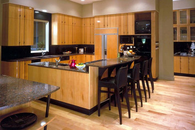 Inspiration for a transitional light wood floor kitchen remodel in Nashville with granite countertops, black backsplash and paneled appliances