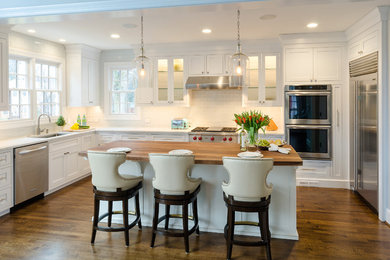 Inspiration for a traditional u-shaped kitchen/diner in Richmond with a submerged sink, shaker cabinets, white cabinets, white splashback, stainless steel appliances, medium hardwood flooring and an island.