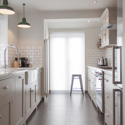 Enclosed kitchen - mid-sized contemporary galley enclosed kitchen idea in London with a farmhouse sink, shaker cabinets, white backsplash and subway tile backsplash