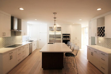 Inspiration for a medium sized contemporary u-shaped open plan kitchen in Los Angeles with a submerged sink, flat-panel cabinets, white cabinets, engineered stone countertops, green splashback, ceramic splashback, stainless steel appliances, light hardwood flooring, an island and white floors.